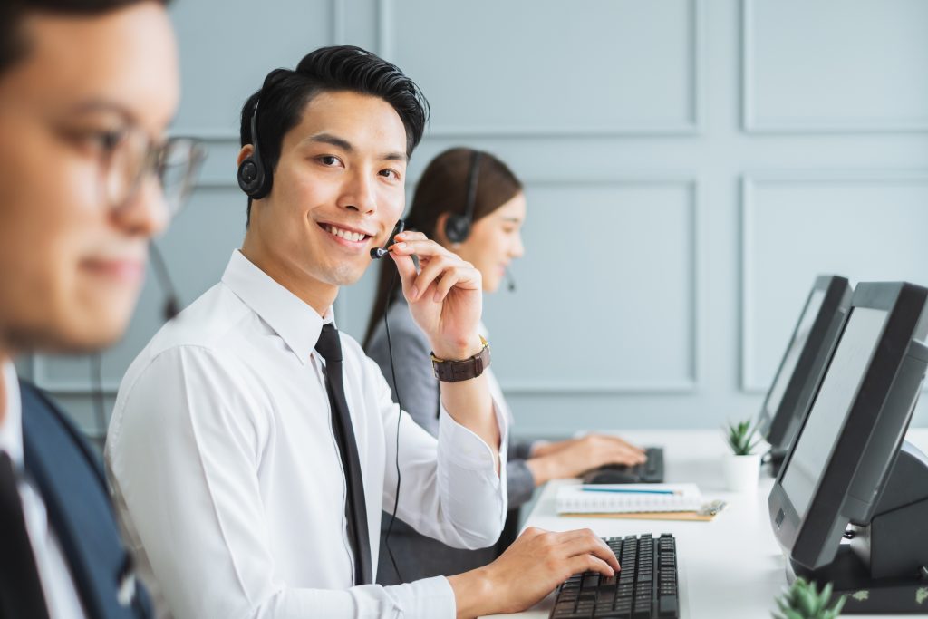 Enhancing Customer Experience in Singapore Through Telemarketing 6 Asian call center team, customer service, telesales in formal suit wearing headset or headphone talking with customer in modern office